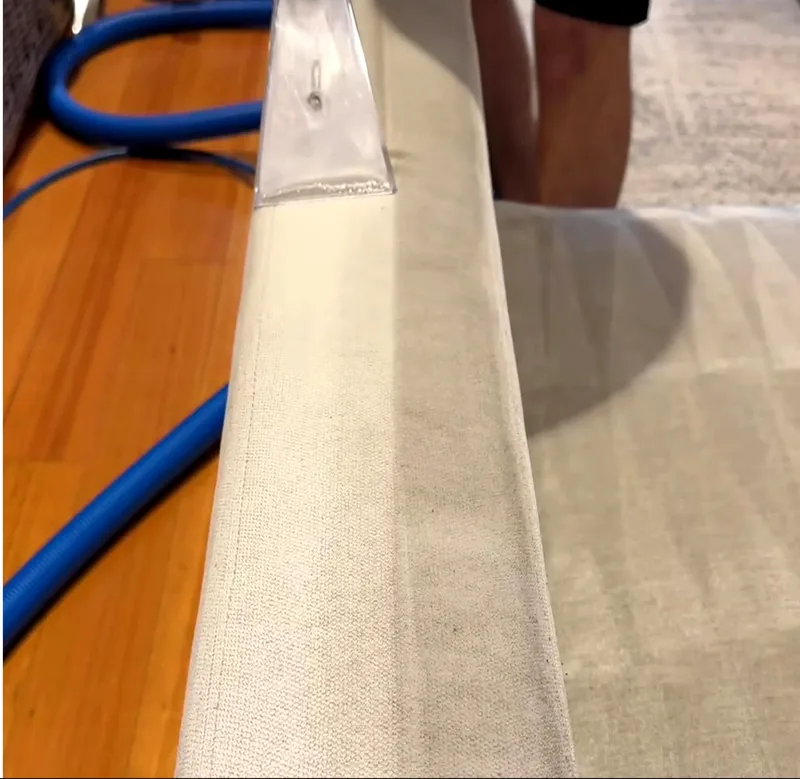 Le même accoudoir de canapé en tissu écru après passage de l'injecteur-extracteur, fibres redressées et teinte uniforme sur toute la longueur de l'assise
